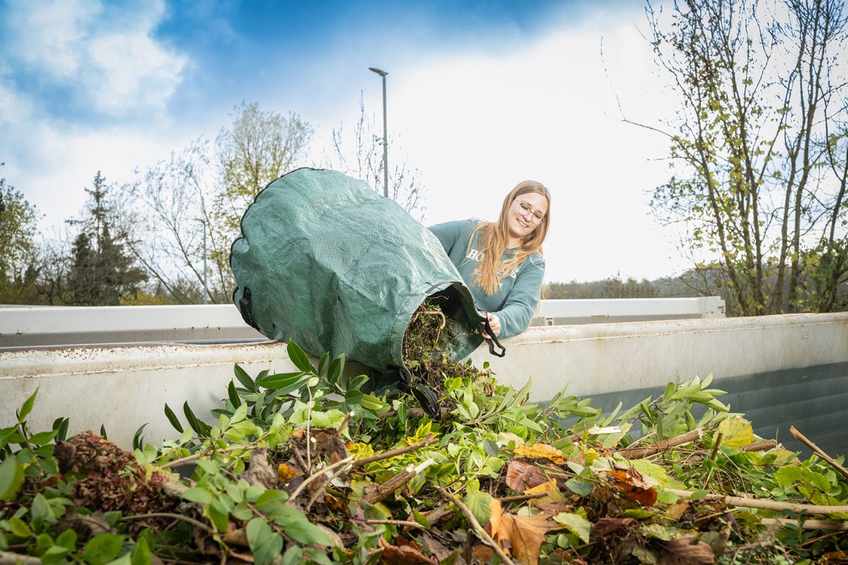 Kundin schüttet Grünschnitt in einen Container